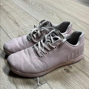 NOBULL Trainers in a light pink color with white branding on the side.